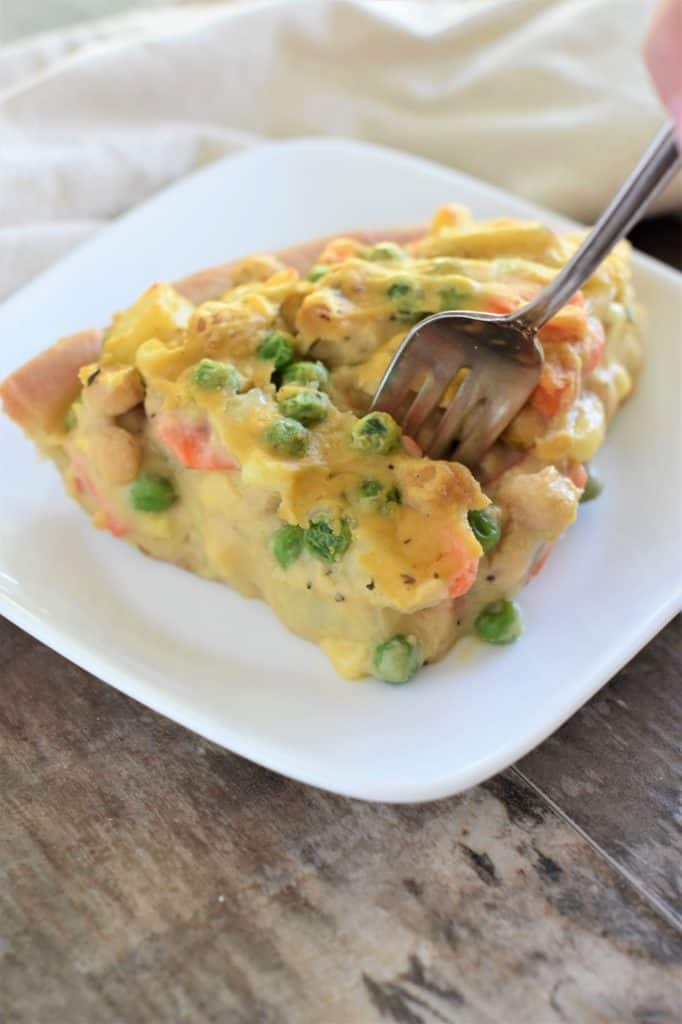 a slice of chickpea pot pie on a white plate with a fork going into it