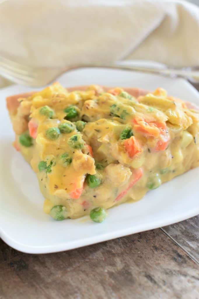 front view of slice of pot pie on a white plate with fork behind it