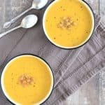 overhead of two bowls of soup with chickpeas on top and spoons on the left