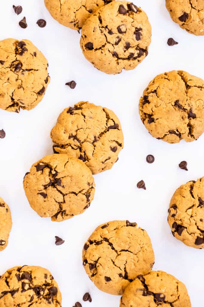 overhead of cookies on a white surface with chocolate chips around them