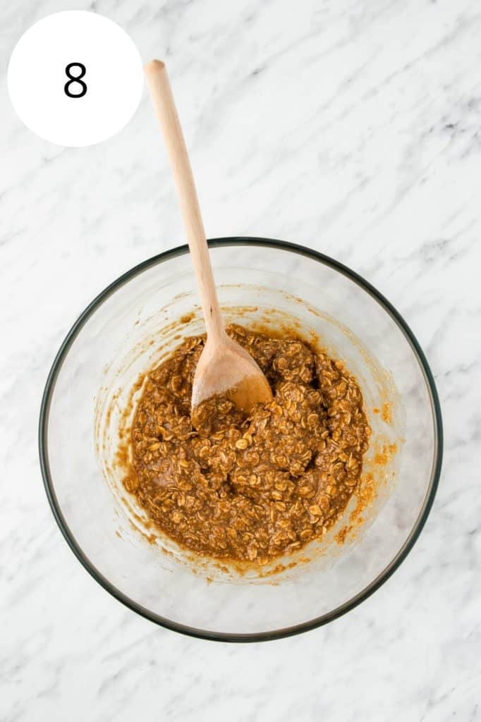 oats mixed into mixture in mixing bowl with wooden spoon