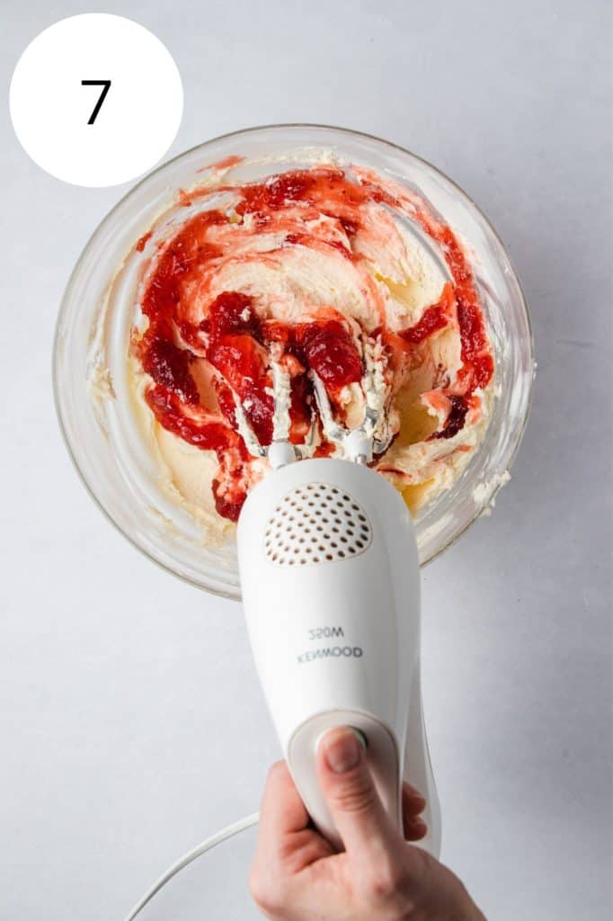 whipping strawberry preserves into the frosting