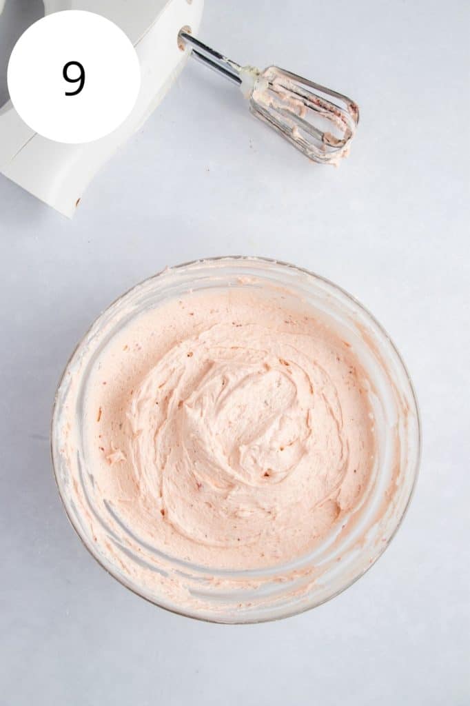 finished frosting in mixing bowl with electric hand mixer behind it