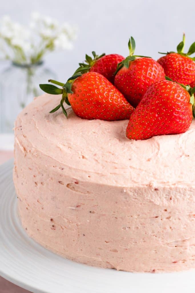 close-up of left side of cake on white cake stand with strawberries on top