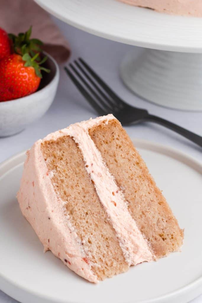 close-up of slice of cake on a white plate with fork behind it