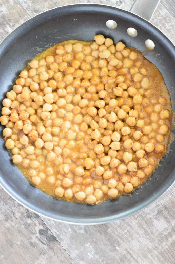 chickpeas mixed with seasonings cooking in pan in vegetable broth