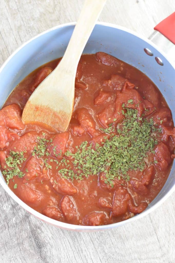 seasonings added to the pot with a wooden spoon in it.