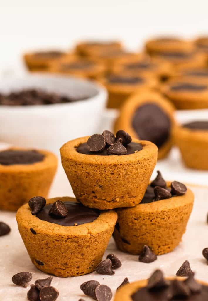 three cookie cups in view with some behind blurred out and chocolate chips around