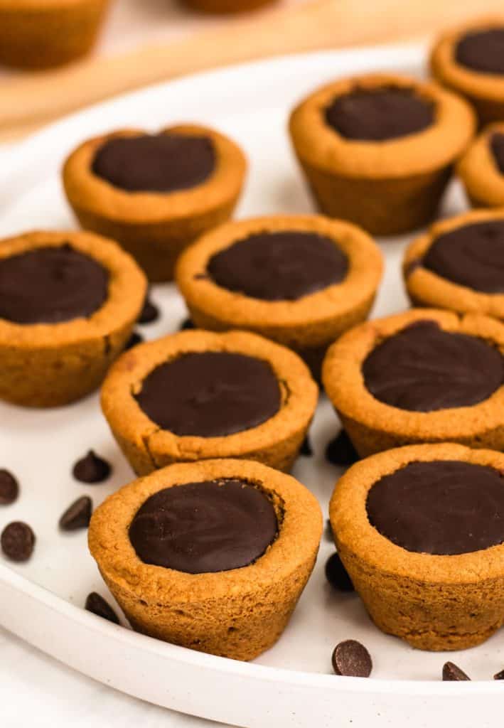 cookie cups on a white serving dish with some chocolate chips around