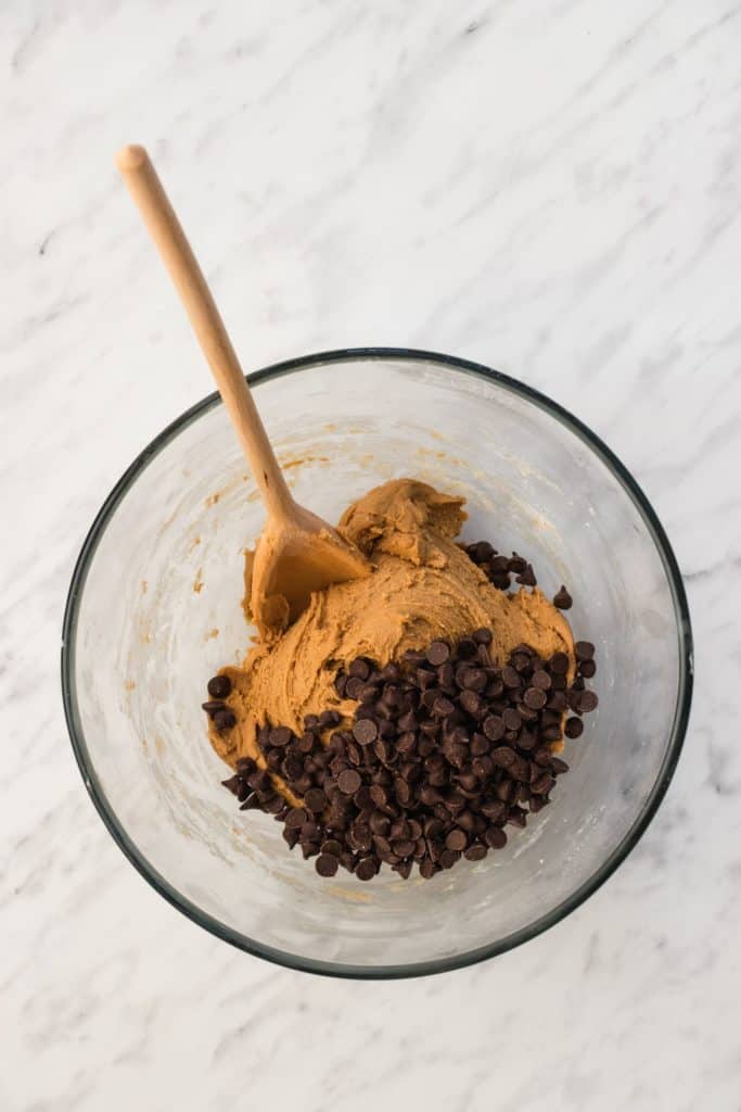 chocolate chips added to the dough with wooden spoon in the bowl