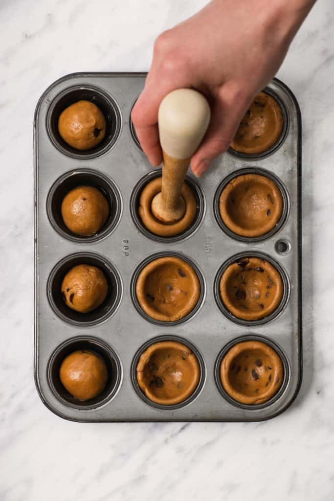 pressing down on dough balls in mini muffin tin