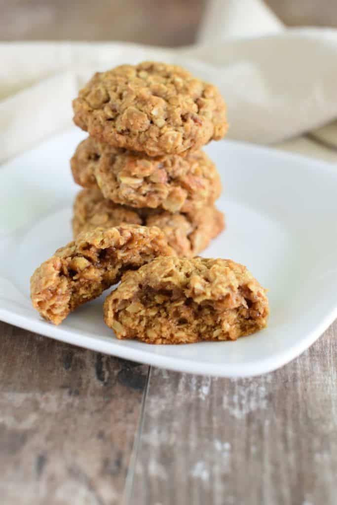 open oatmeal coconut pecan cookie in front of 2 cookies stacked up on a white plate