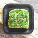 close-up of avocado toast with arugula and pine nuts