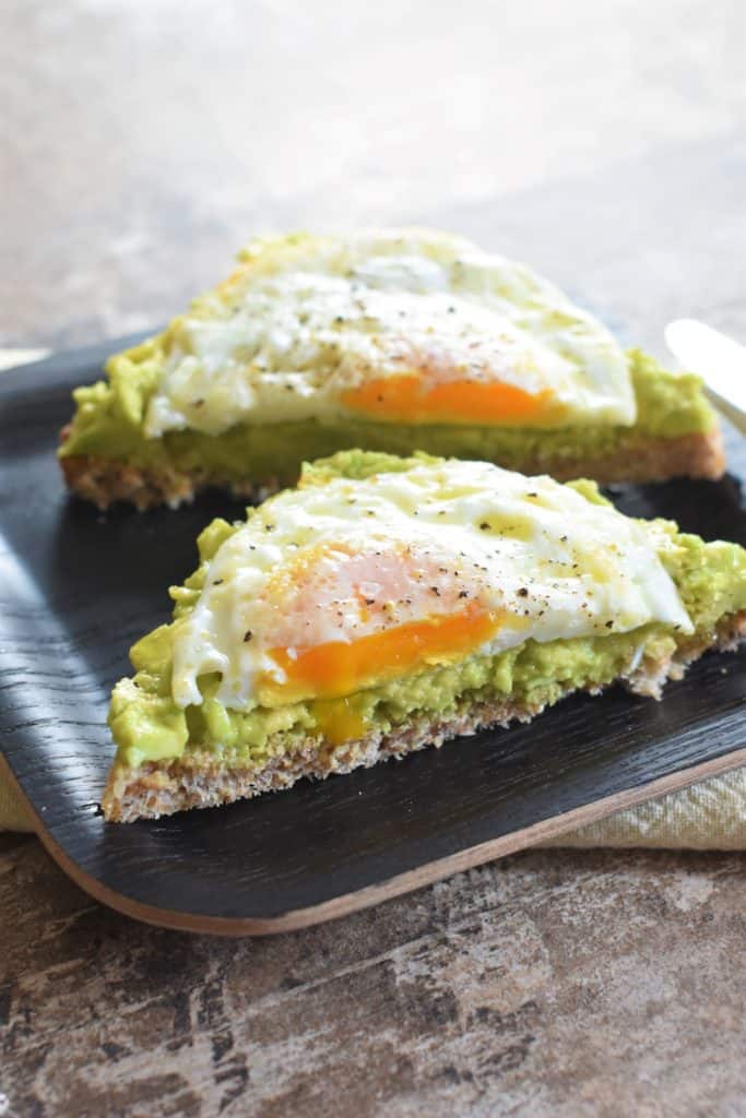 front view of cut piece of avocado toast with fried egg