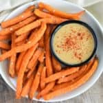 overhead close-up of fries on a white plate with mustard dipping sauce