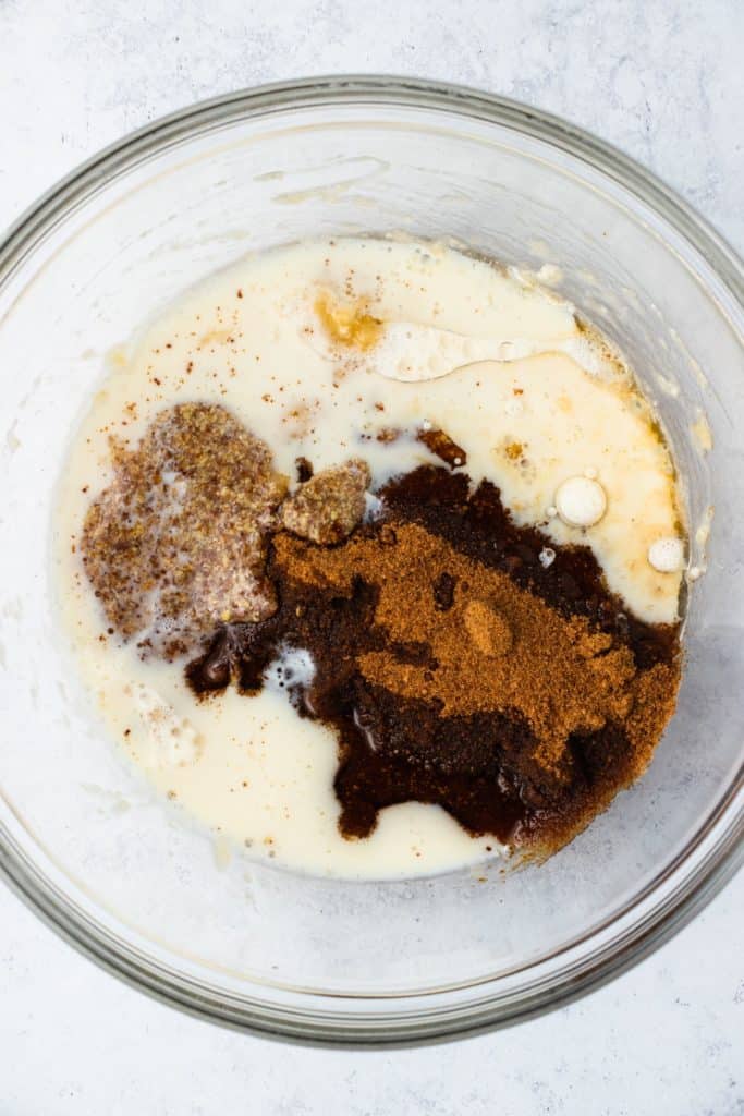 remaining wet ingredients added to bananas in mixing bowl