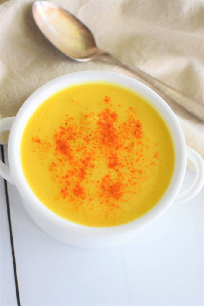 overhead of hollandaise in a small white serving bowl garnished with some paprika