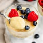 close-up of spoonful of pudding over the rest of the serving in a glass container with berries in it