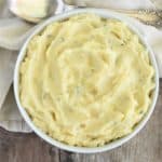 close-up overhead of mashed potatoes in white bowl with spoon behind it