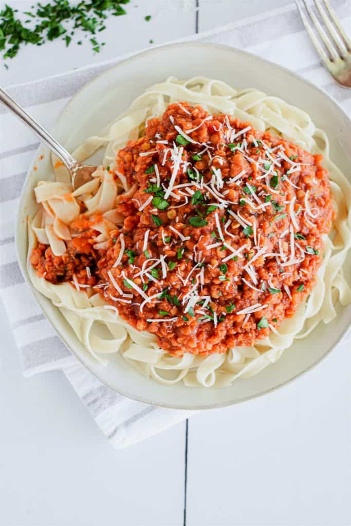 overhead of pasta with sauce sprinkled with parsley and Parmesan and a fork in it on the left side