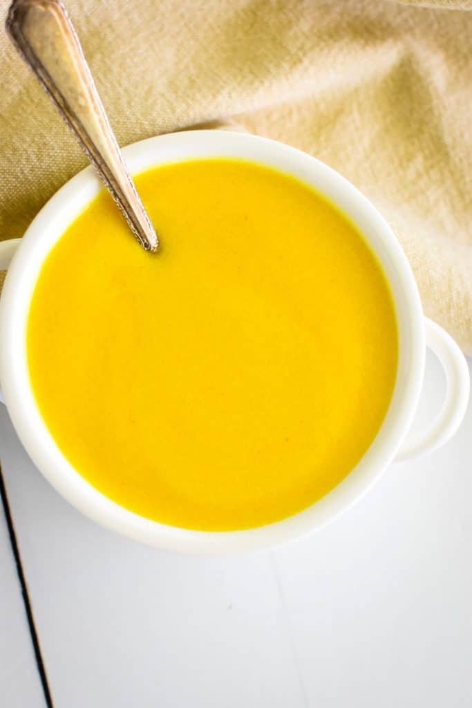 overhead of hollandaise in a small white serving bowl with a spoon in it