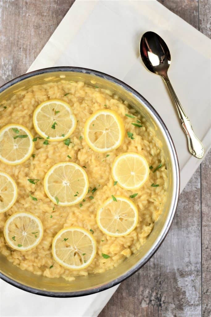 overhead of vegan lemon risotto in the pan partially cut off on the left and with a wooden spoon on the right