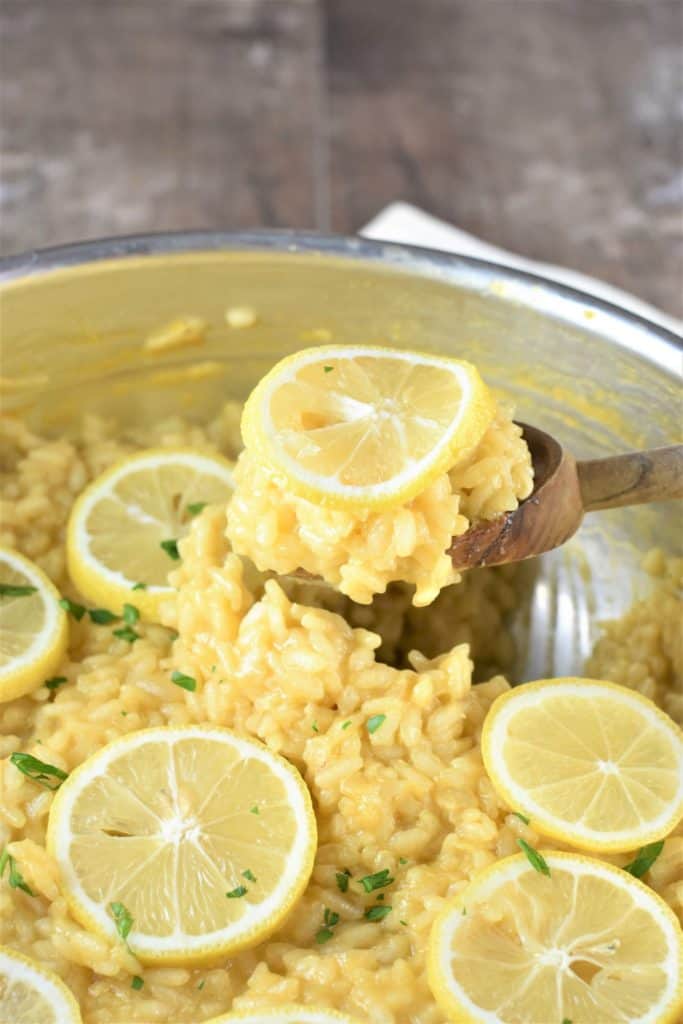 scooping some risotto out of the pan with a wooden spoon