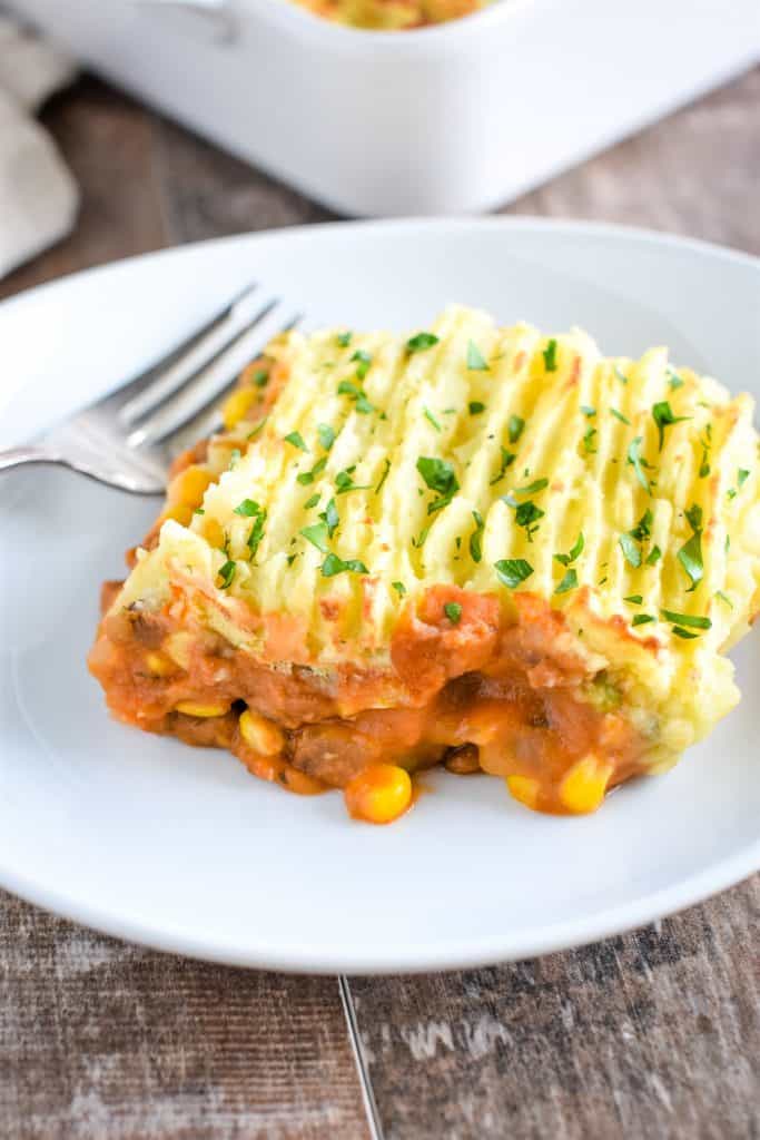 front overhead view of piece of shepherd's pie on a white plate with a fork