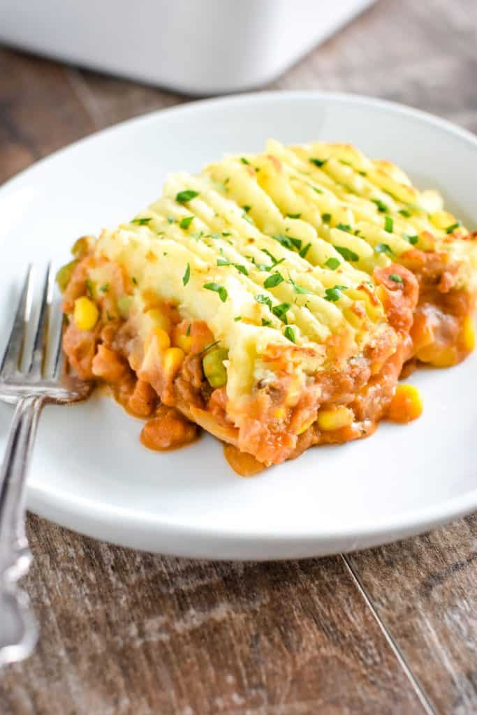 piece of vegan shepherd's pie on white plate with fork