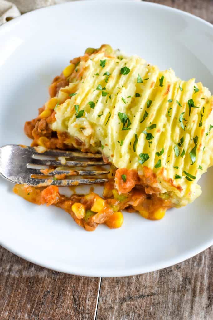 overhead of piece of shepherd's pie on a white plate with a fork in it