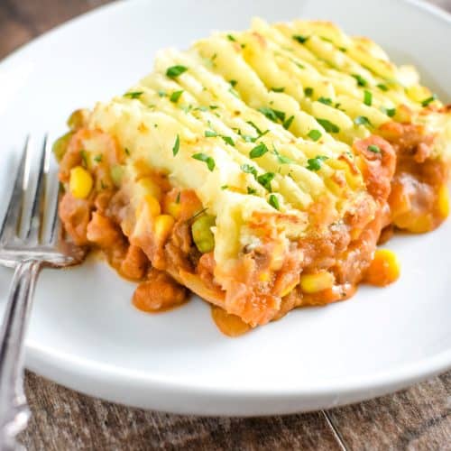 piece of shepherd's pie on a white plate with a fork next to it