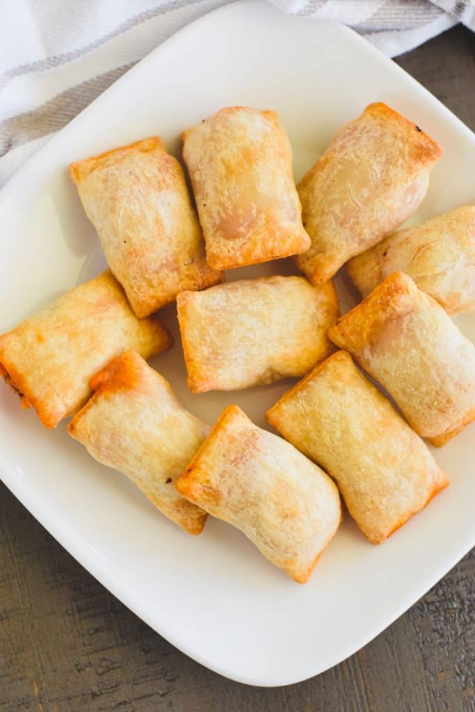 overhead of gluten-free pizza rolls on white plate.