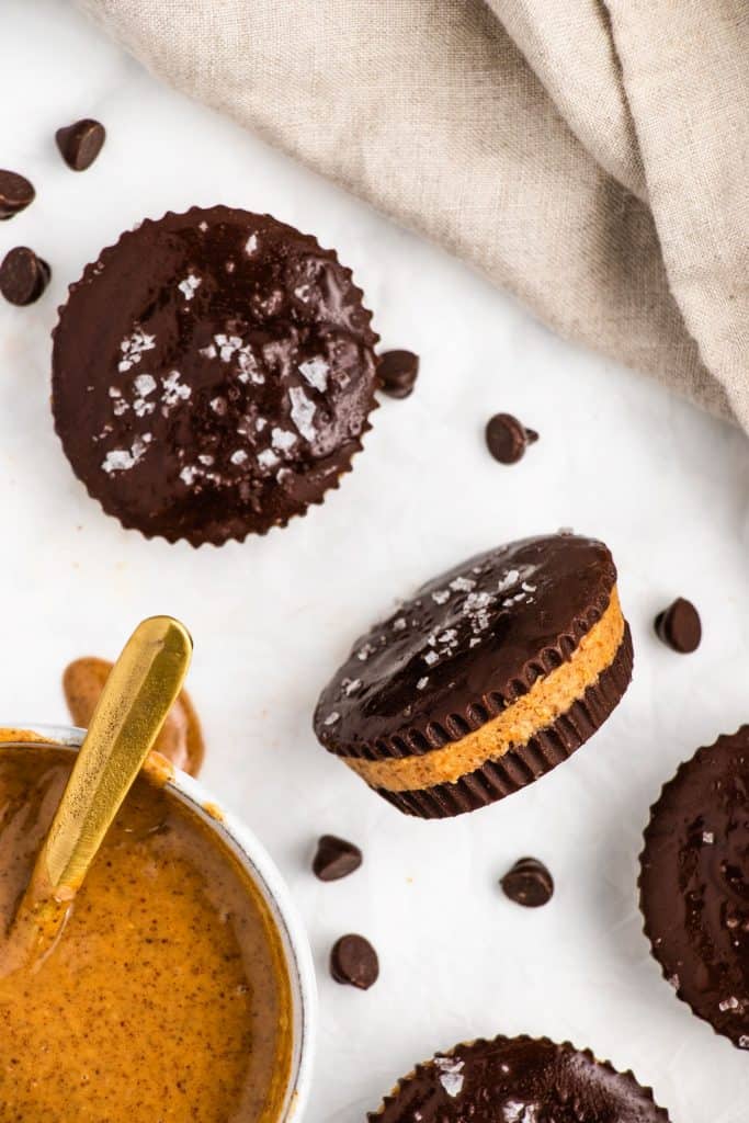 peanut butter cup turned on its side to see the layers with some more around it and some peanut butter in a bowl