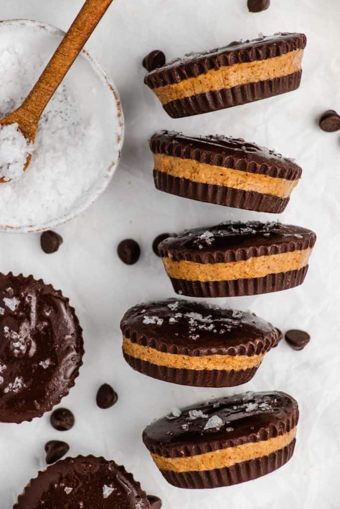 five peanut butter cups turned on their side to see the layers and a bowl of salt with spoon in it