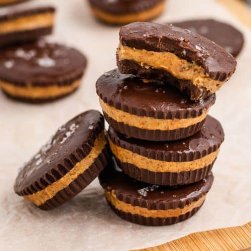 stack of peanut butter cups with with bite taken out of top one and one leaning on the stack to the left and some more in the background