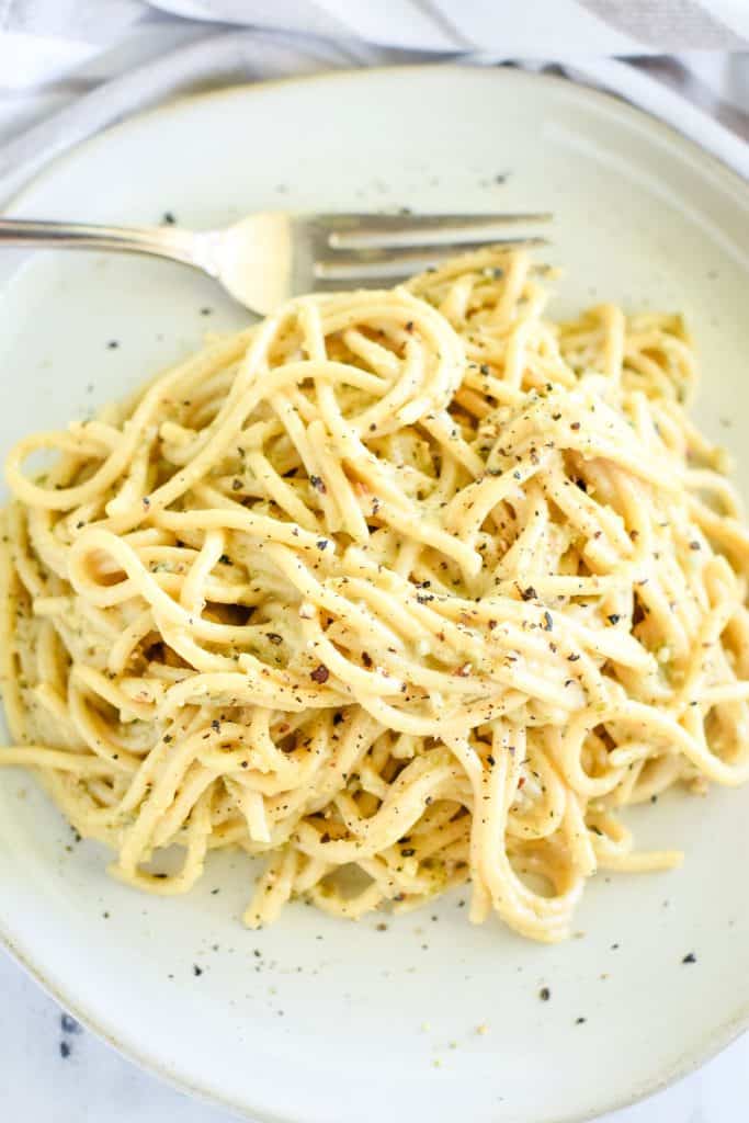 close-up overhead of pasta on white dish garnished with pepper and a fork at the top of the plate