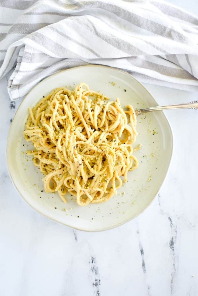 overhead of pasta on white plate with some wrapped around a fork at the top coming in from the right