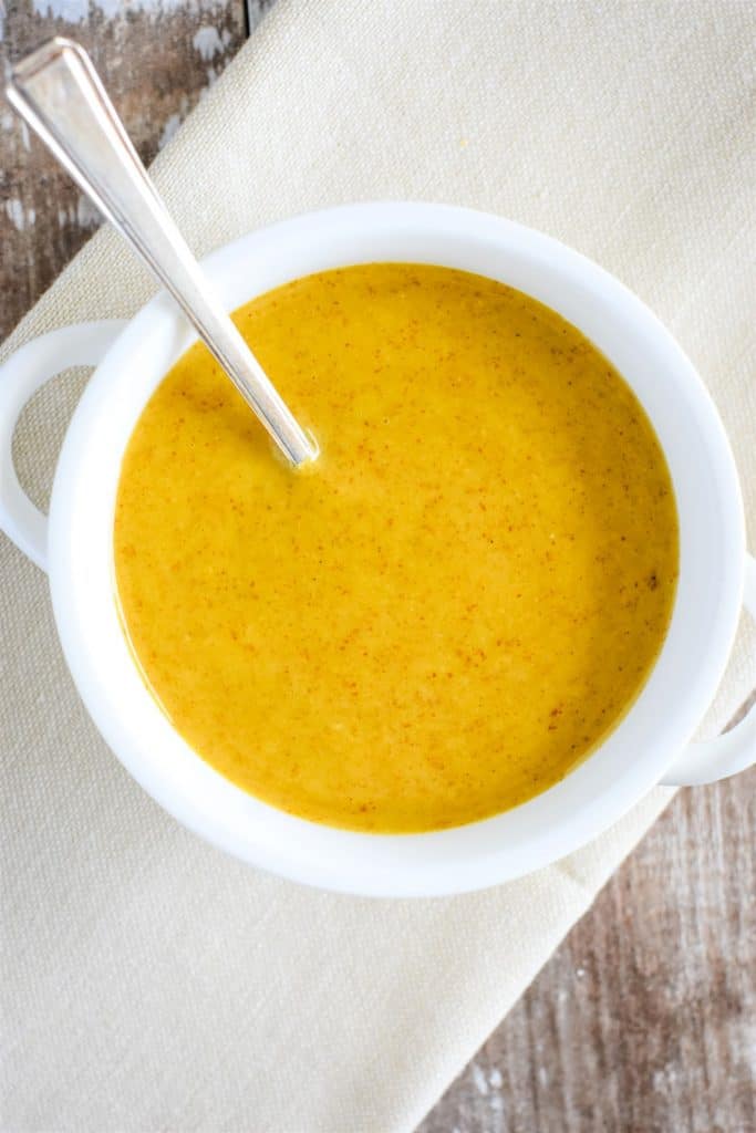 overhead of vegan honey mustard in white bowl with a spoon in it