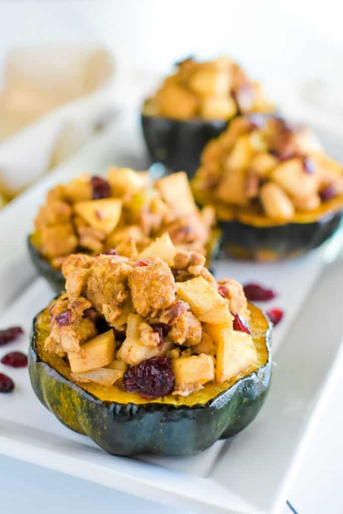 front close-up view of 1 serving of acorn squash on white serving platter with 3 more blurred out behind it