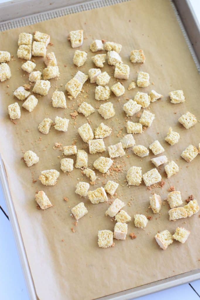 bread cubes on parchment-lined baking sheet after toasting in oven