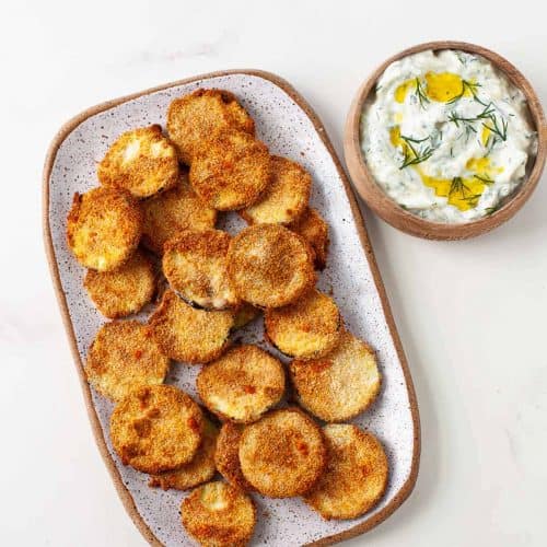 overhead of zucchini chips on serving platter with side of dipping sauce