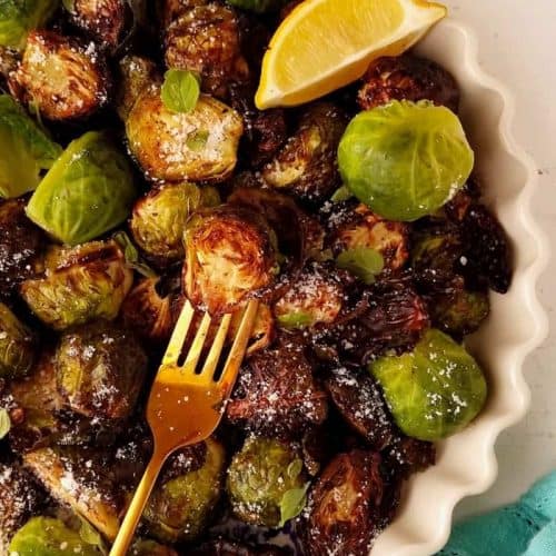 fork taking one of the Brussels sprouts from the serving dish of the rest of them