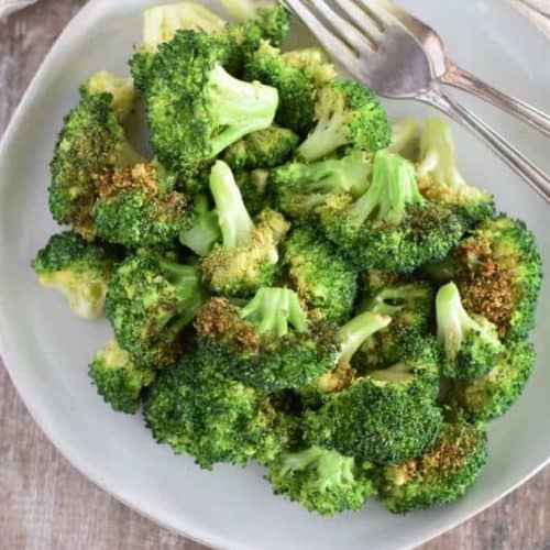 overhead of broccoli on white plate with two forks