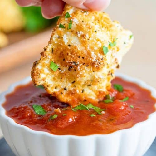 dipping a toasted ravioli into a cup of sauce