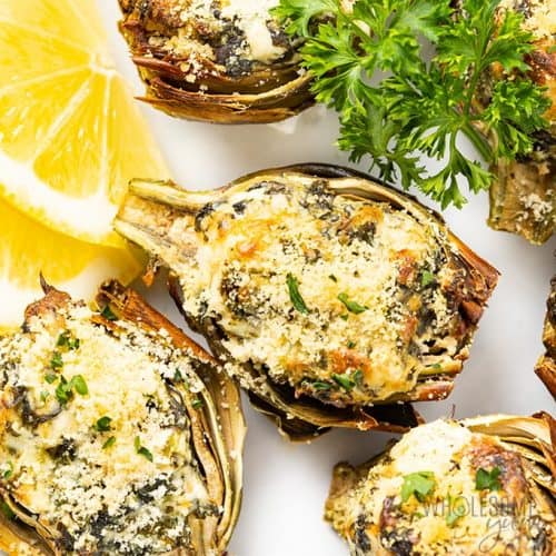 overhead of stuffed baby artichokes with lemon and parsley garnish