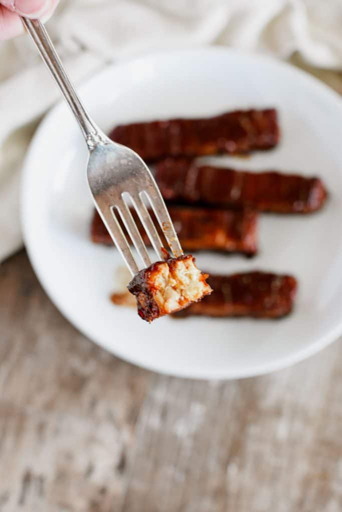 holding a fork with a piece of tempeh.