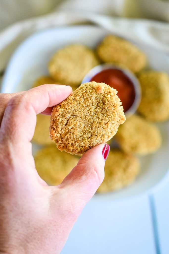 holding a nugget over the rest on a plate below