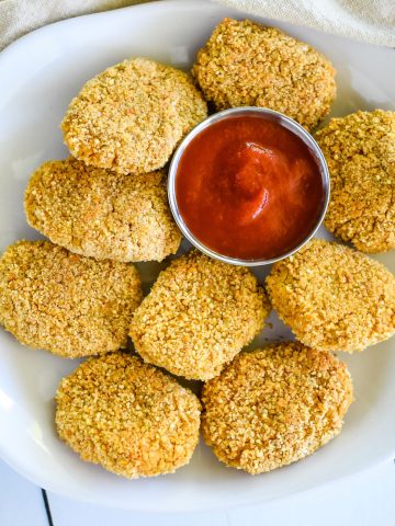 close-up overhead of nuggets on a white plate with cup of ketchup on the plate