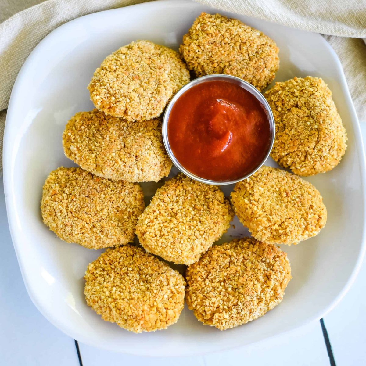 close-up overhead of nuggets on a white plate with cup of ketchup on the plate