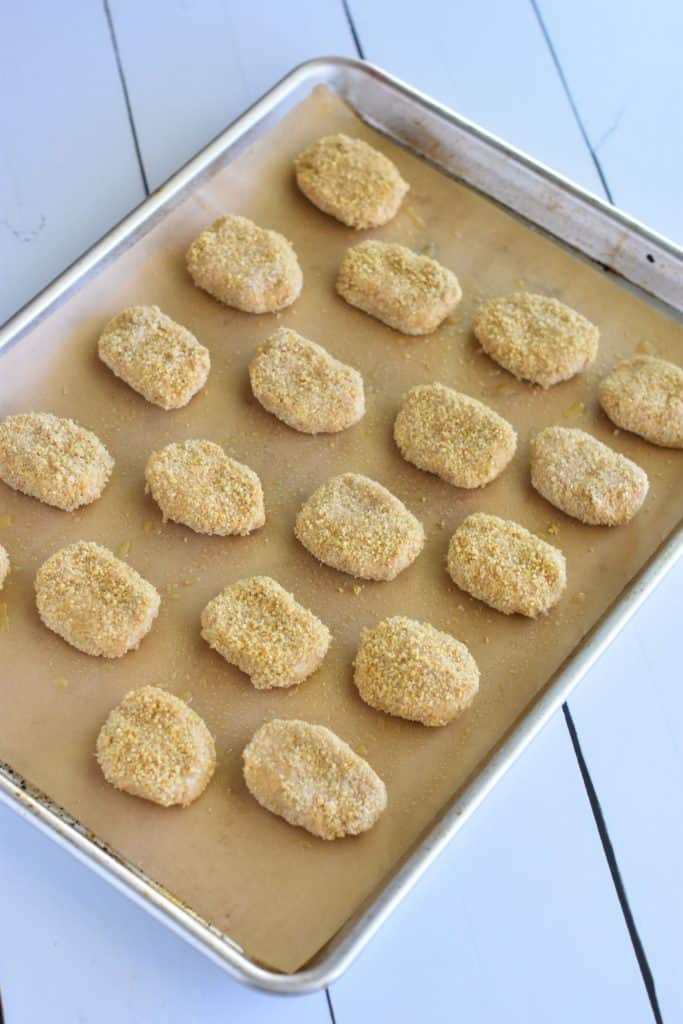 breaded nuggets on parchment-lined baking sheet before cooking